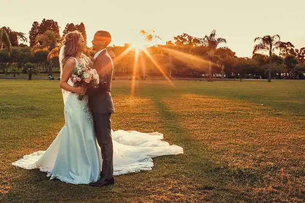 Noivos ao entardecer, com o pôr do sol iluminando o jardim da Lagoa Eventos