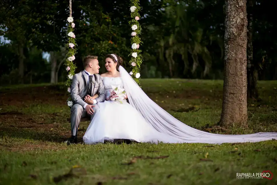 Noivos sentados em balanço decorado com rosas no jardim