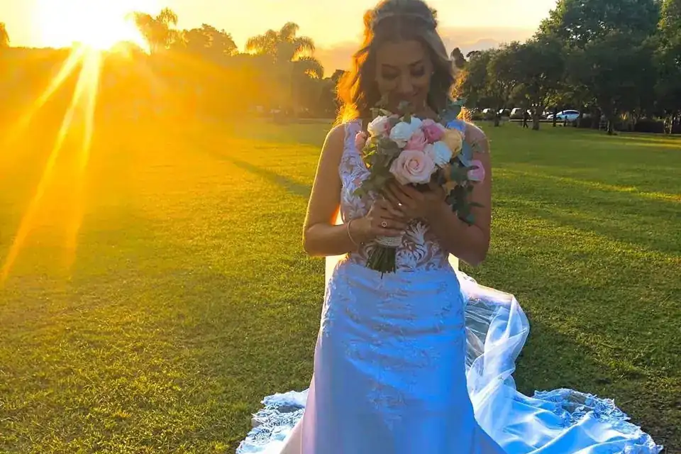 Noiva ao pôr do sol, cheirando o buquê de flores
