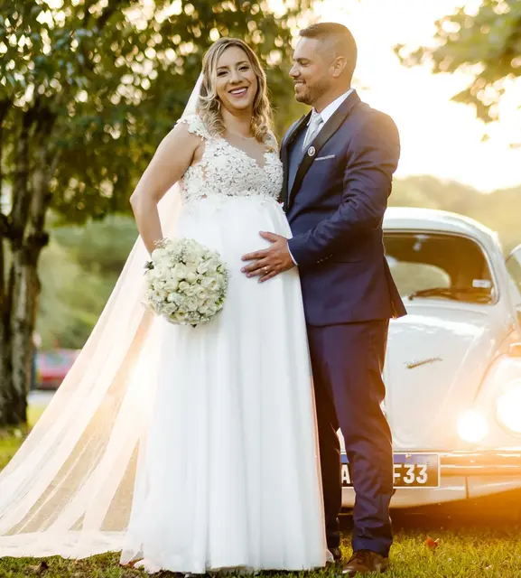 Noiva grávida ao lado de fusca branco, ao entardecer